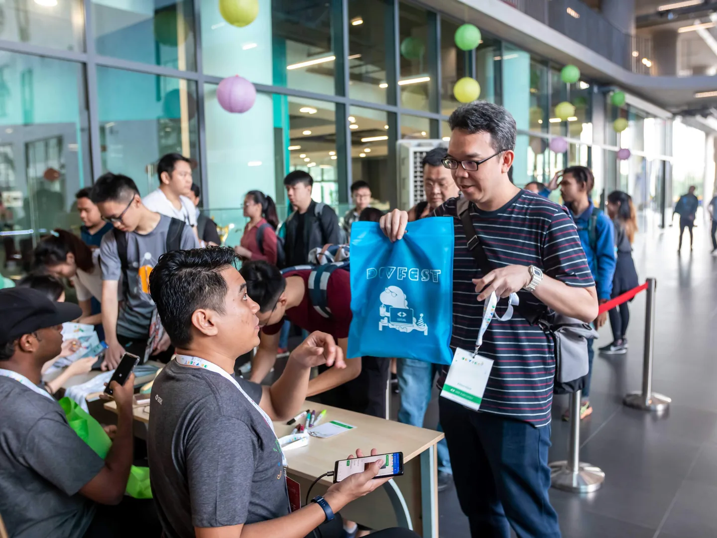 Crew checking guests in on their phones at the registration desk of DevFest Kuala Lumpur, run by Annex CS